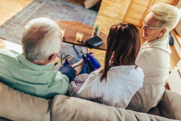 Young medic taking blood pressure during home visit