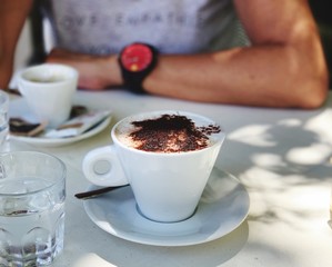 cappuccino with woman and black coffee in background