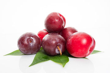 plums with plum leaves on a white background