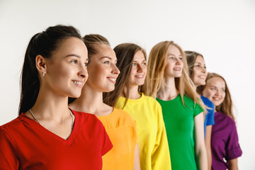 Young women weared in LGBT flag colors isolated on white background. Caucasian female models in bright shirts. Look happy, smiling. Trust LGBT pride, human rights, freedom of choice concept.