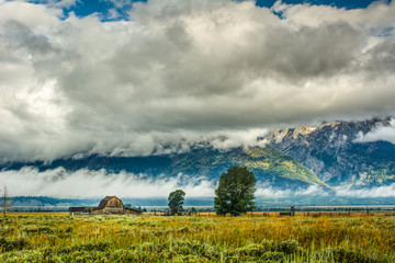 Obraz premium Barn in Expansive Field Below Dramatic Cloud-Covered Tetons - 2
