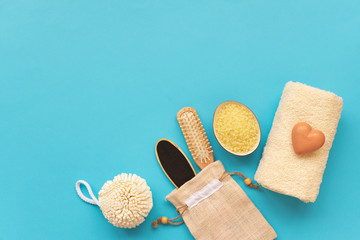 Bath accessories: towel, salt, brush, wisp, pumice and soap on blue background. Spa cosmetic or hygiene concept. Copy space. Flat lay. Top view. Flat lay