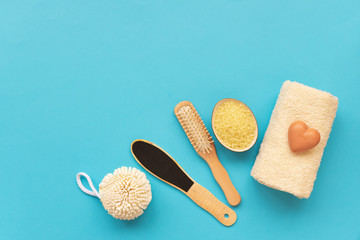 Bath accessories: towel, salt, brush, wisp, pumice and soap on blue background. Spa cosmetic or hygiene concept. Copy space. Flat lay. Top view. Flat lay