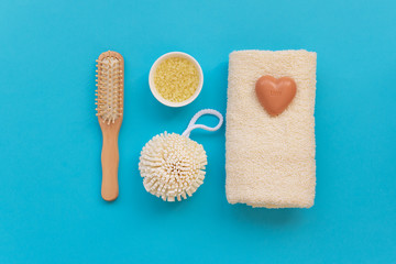 Fototapeta na wymiar Bath accessories: towel, salt, brush, wisp, pumice and soap on blue background. Spa cosmetic or hygiene concept. Copy space. Flat lay. Top view. Flat lay