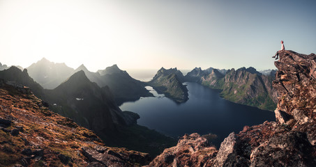 Person sitting on the edge of the cliff watching sunset in the mountains.. Lofoten Islands.