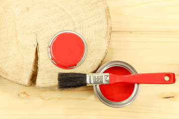Red enamel paint and brush, wooden background. Flat composition.