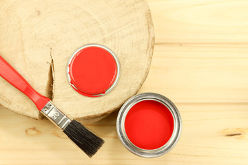 Red enamel paint and brush, wooden background. Flat composition.