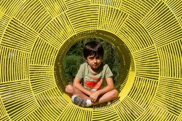Young child sitting on the yellow sculpture in the forest