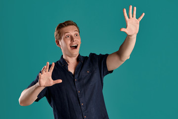 Close-up portrait of a ginger guy in navy t-shirt posing on blue background. Sincere emotions.