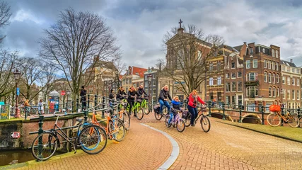 Foto auf Glas Stadtbild an einem sonnigen Wintertag - Blick auf die Radfahrergruppe im historischen Zentrum von Amsterdam, Niederlande © rustamank