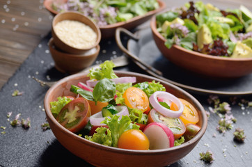 Vegetable salad of lettuce, cherry tomatoes, radish, cucumber, onion and basil on slate stone tray