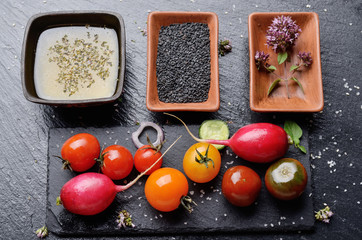 Top view at fresh organic vegetables on slate stone tray with spices and sauces aside closeup dark concept photo