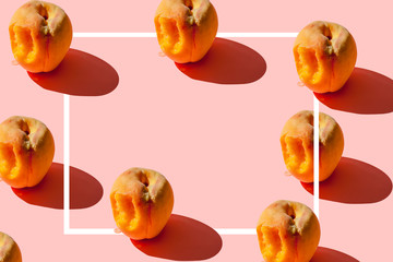Pattern of many juicy ripe peaches on a pastel pink background with a white frame in the center for...
