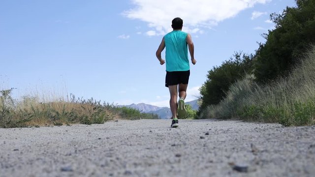 Slow Motion Shot of a active man going trail running on the outdoor mountainous trails of Draper City, Utah. The Wasatch Mountains can be seen in the background.
