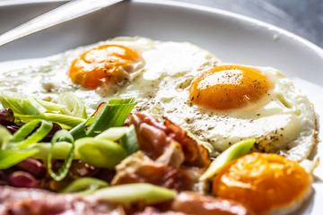 English Breakfast with eggs, bacon, beans and iyoung onion in white plate