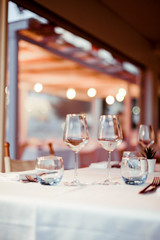 A glass of white wine on a table in a restaurant. Toned photo. Glare and light spots. Free space for text.