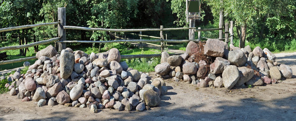Fototapeta na wymiar Two large piles of granite boulders and stones lie near a village fence