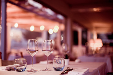 A glass of white wine on a table in a restaurant. Toned photo. Glare and light spots. Free space for text.
