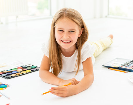 little girl draws lying on the floorlittle cheerful girl draws lying on the floor