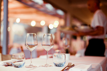 A glass of white wine on a table in a restaurant. Toned photo. Glare and light spots. Free space for text.