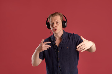 Close-up portrait of a ginger guy in navy t-shirt posing on pink background. Sincere emotions.