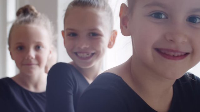 Close up of faces of four little Caucasian ballerinas looking at camera and smiling
