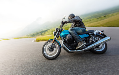 Fototapeta na wymiar Motorcycle driver riding in Alpine landscape.