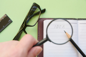 The inscription "Idea" under the magnifying glass in the hands of a person. Idea search concept. Flat lay