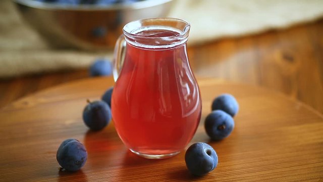 sweet compote of autumn blue plums in a glass decanter on a wooden table
