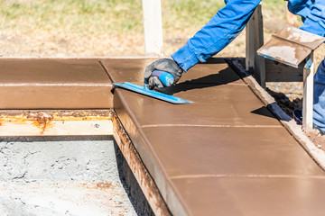 Construction Worker Using Trowel On Wet Cement Forming Coping Around New Pool