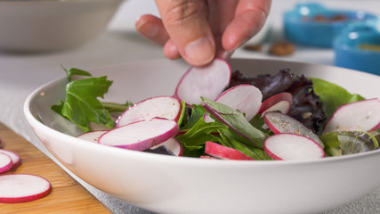  Herb Mix Salad with Fresh Organic Radish, Lettuces, Spinach, Some Seasoning, Almonds and Vegetable Oil. Close Up on White Background, Woman Hands