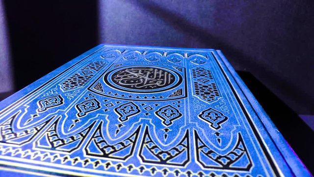 Blue Quran on a dark background, close-up. Islam. Religion.