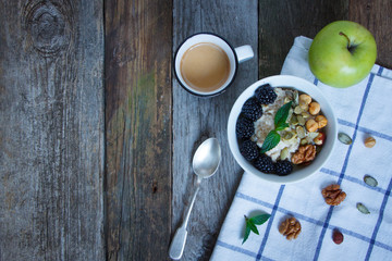 Top view oatmeal porridge, coffee, apple, berries and nuts on a wooden table, selective focus