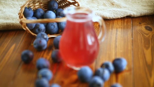 sweet compote of autumn blue plums in a glass decanter on a wooden table