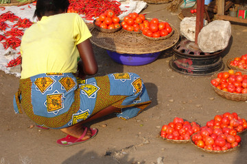 Benin, Cotonou. African woman squatting to sell tomatoes 