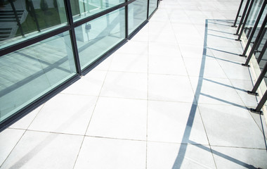 Fototapeta premium urban modern city background tile pavement floor view near glass exterior facade building and shadows from fence, copy space for text