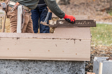 Construction Worker Leveling Wet Cement Into Wood Framing