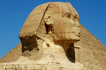 EGYPT, Giza. Head of the Sphynx with a pyramid in the background. 