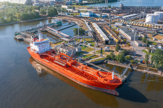 Aerial view large port with railway infrastructure for the delivery of bulk cargo by sea, loading oil using a pump station in ship tanker for transportation and delivery.