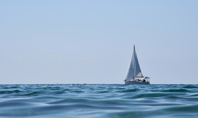 Sailing yacht in sea on background of blue sky.