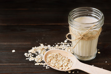 Glass of vegan oat milk and Oat on a table, space for text.