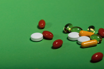 Bright colored pills on a green background.Close-up, side view.
