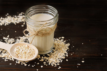 Glass of vegan oat milk and Oat on a table, space for text.