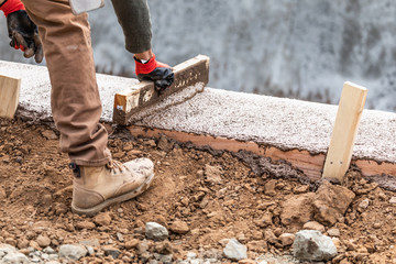 Construction Worker Leveling Wet Cement Into Wood Framing