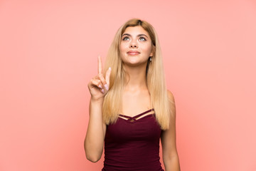 Teenager girl over isolated pink background pointing with the index finger a great idea