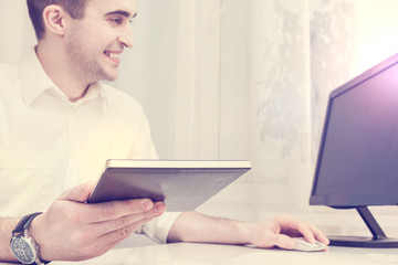 The man works in the office and holding a tablet, front view, close up, toned