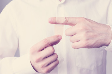 Obraz premium Stick plaster on finger, man with a wound on his finger medical plaster, men's hands, close up, toned