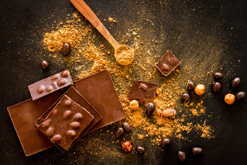Chocolate splash bars and nuts on black table background top view