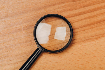 Small magnifying glass on wooden table, search symbol