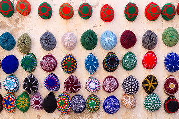 Morocco, Essaouira. Colorful men's hats (tagiya) hanging on wall.